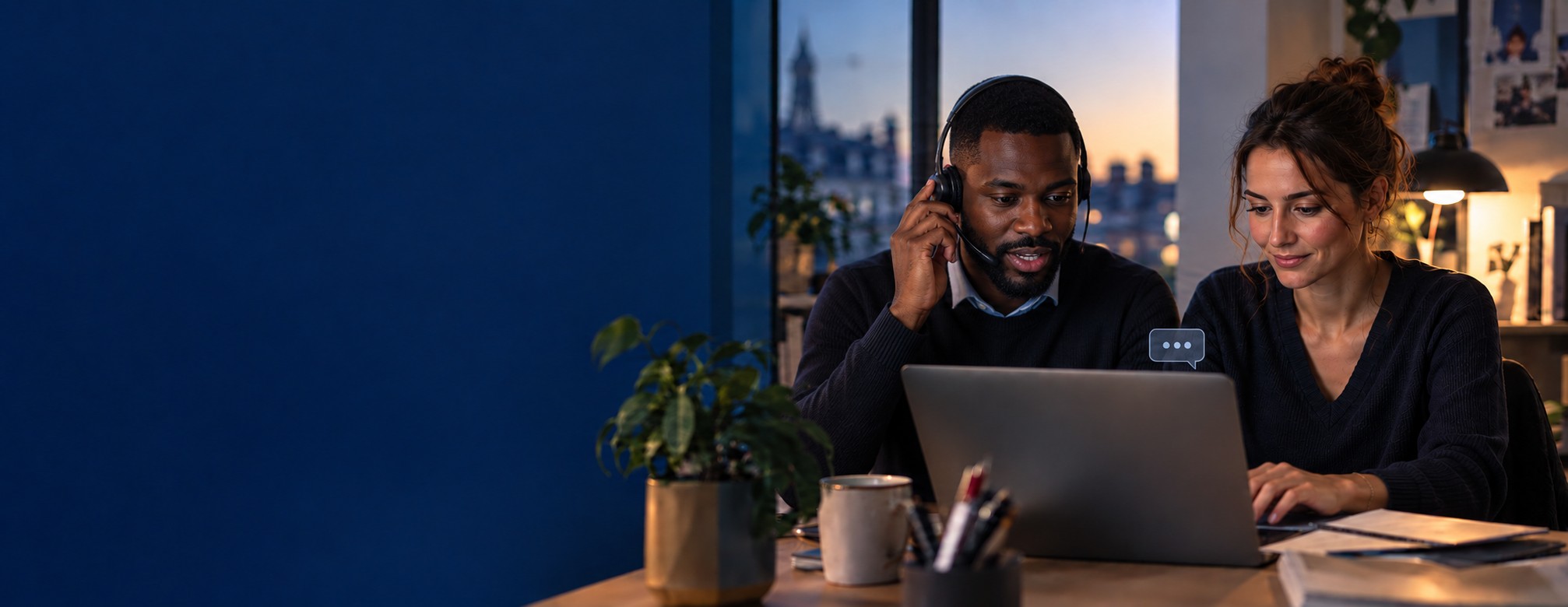 Assistant NOMADE IA : un conseiller et une conseillère prennent un appel client, casque sur les oreilles, devant un ordinateur portable, en fin de journée.